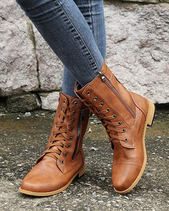 Gli stivaletti cuoio coi jeans stretti, sul marciapiede bagnato