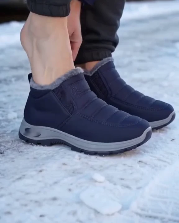 Il piede entra nella scarpa blu notte, in piedi, tenendo la linguetta dietro