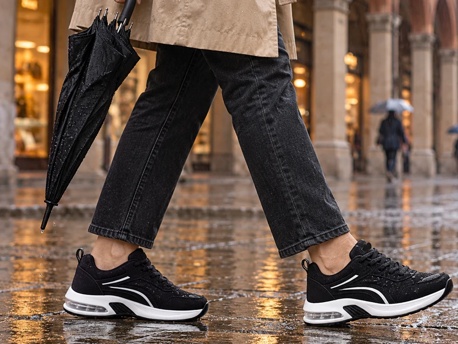 Sneaker nere con le gocce di pioggia sopra, su una strada di pietra bagnata