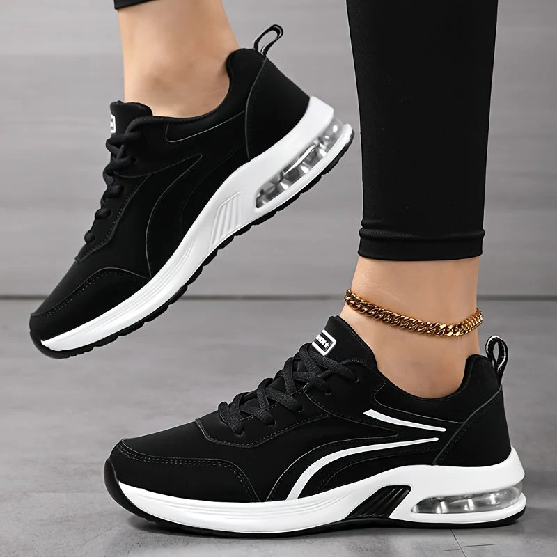 Sneaker nere e bianche ai piedi, con i leggings, viste di lato